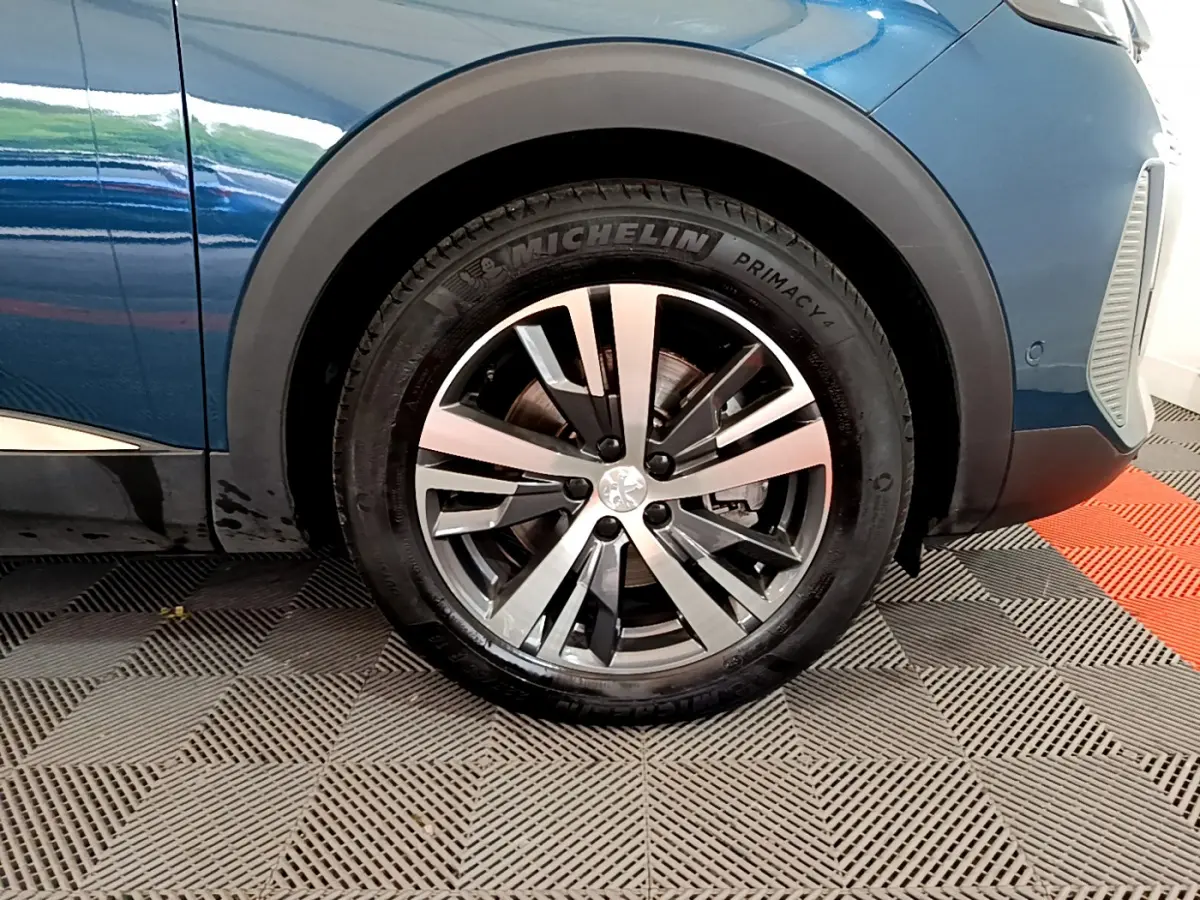 Gros plan sur la roue avant gauche d’un Peugeot 3008 bleu avec jante alliage et pneu Michelin Primacy.