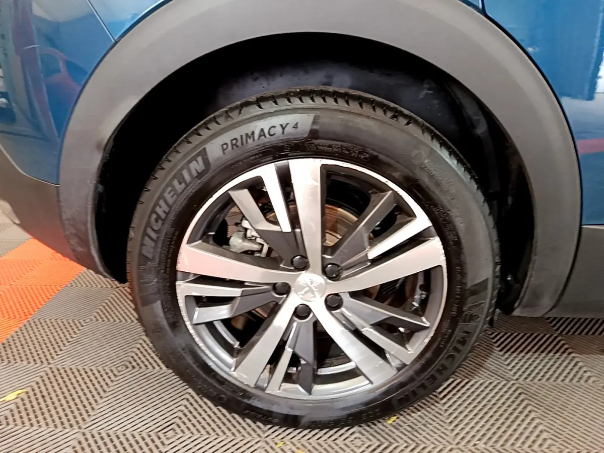 Gros plan sur la roue avant gauche du Peugeot 3008 bleu hybride avec jante alliage et pneu Michelin Primacy 4.