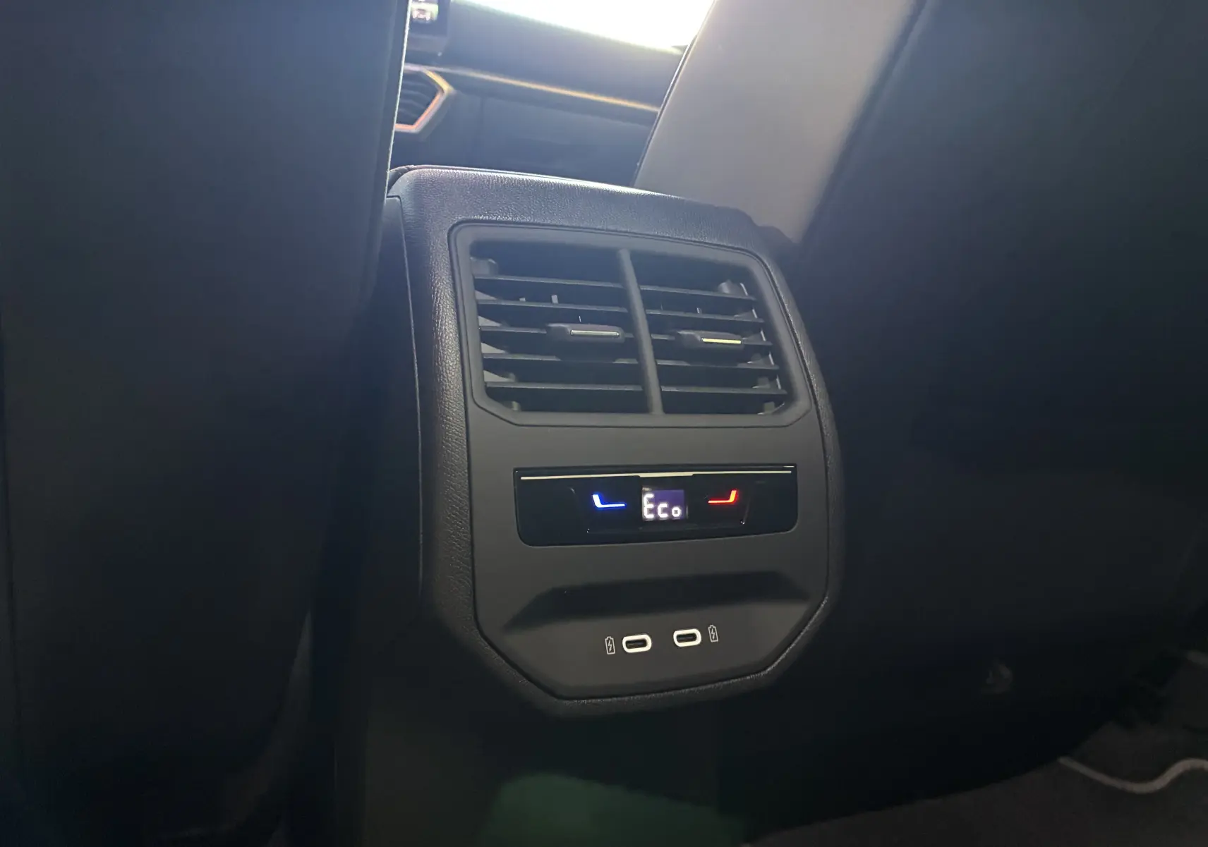 Vue rapprochée de la console arrière noire avec aérateurs, commandes climatisation et ports USB du CUPRA Formentor bleu.