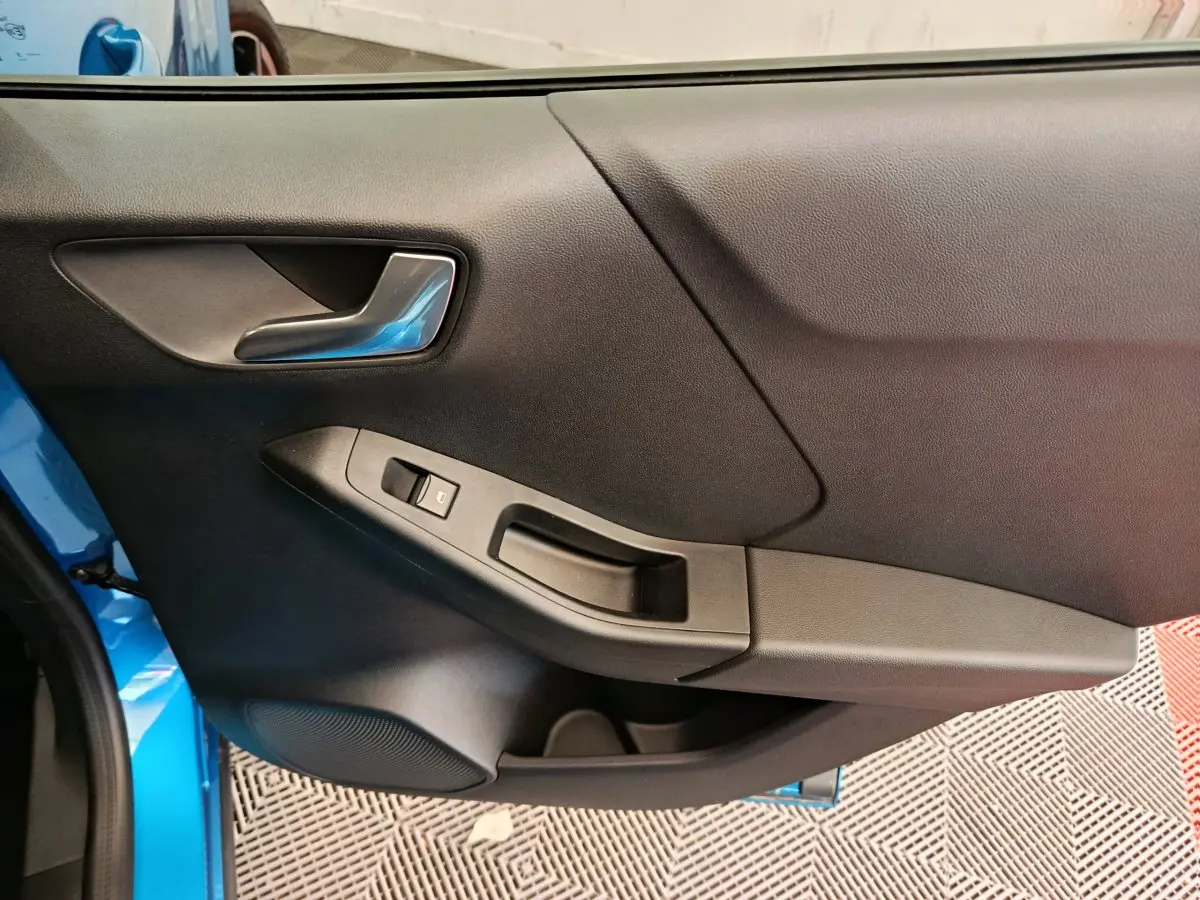 Vue rapprochée de la porte côté gauche du Ford Puma bleu 2025, avec poignée argentée et commande de vitre noire.