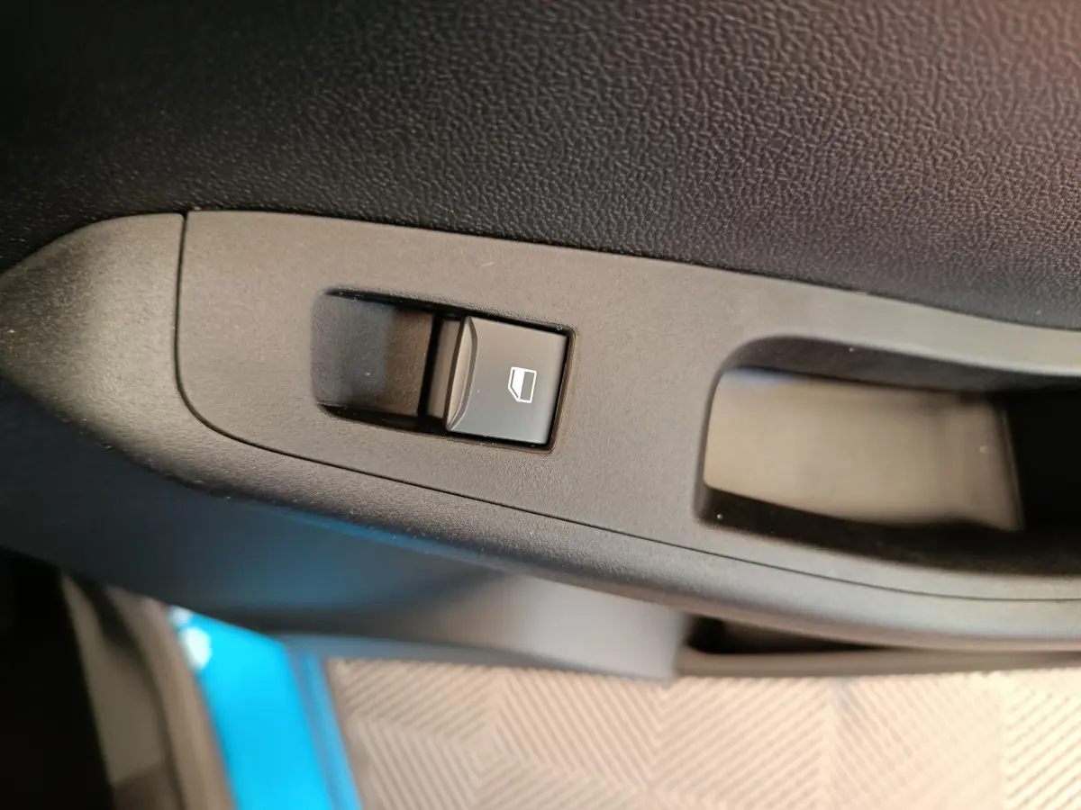 Bouton de commande de lève-vitre côté conducteur sur porte intérieure noire du Ford Puma bleu 2025.