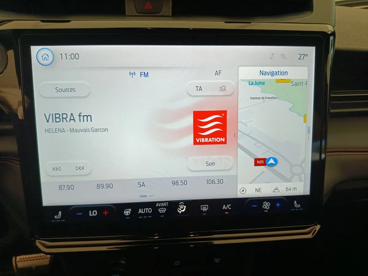 Écran tactile central du tableau de bord du Ford Puma 2025 affichant radio et navigation, ambiance intérieure sombre.