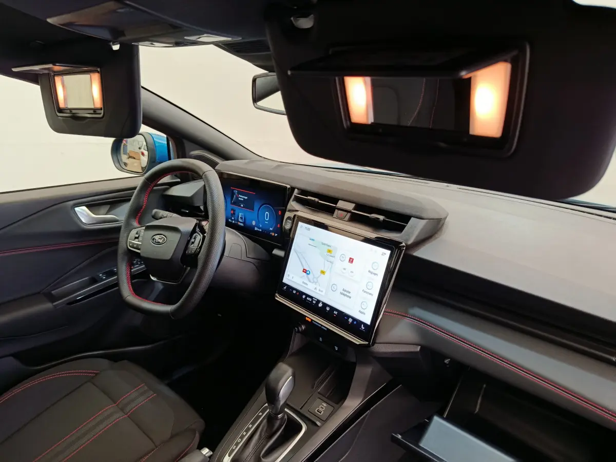 Vue intérieure côté conducteur du Ford Puma 2025 bleu, tableau de bord moderne avec écran tactile et volant cuir noir.