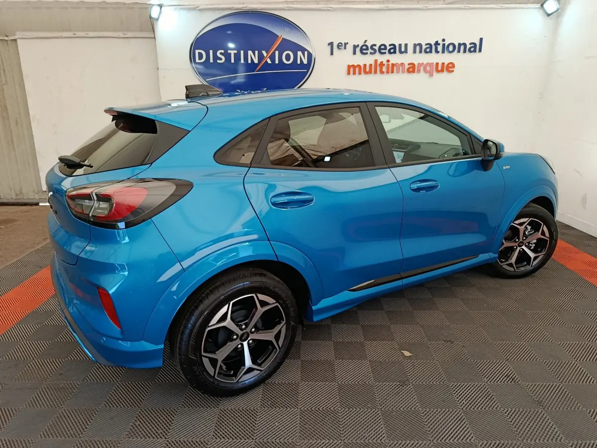 Vue 3/4 arrière droite du Ford Puma bleu ST-LINE 2025 avec jantes alliage et vitres teintées en showroom.
