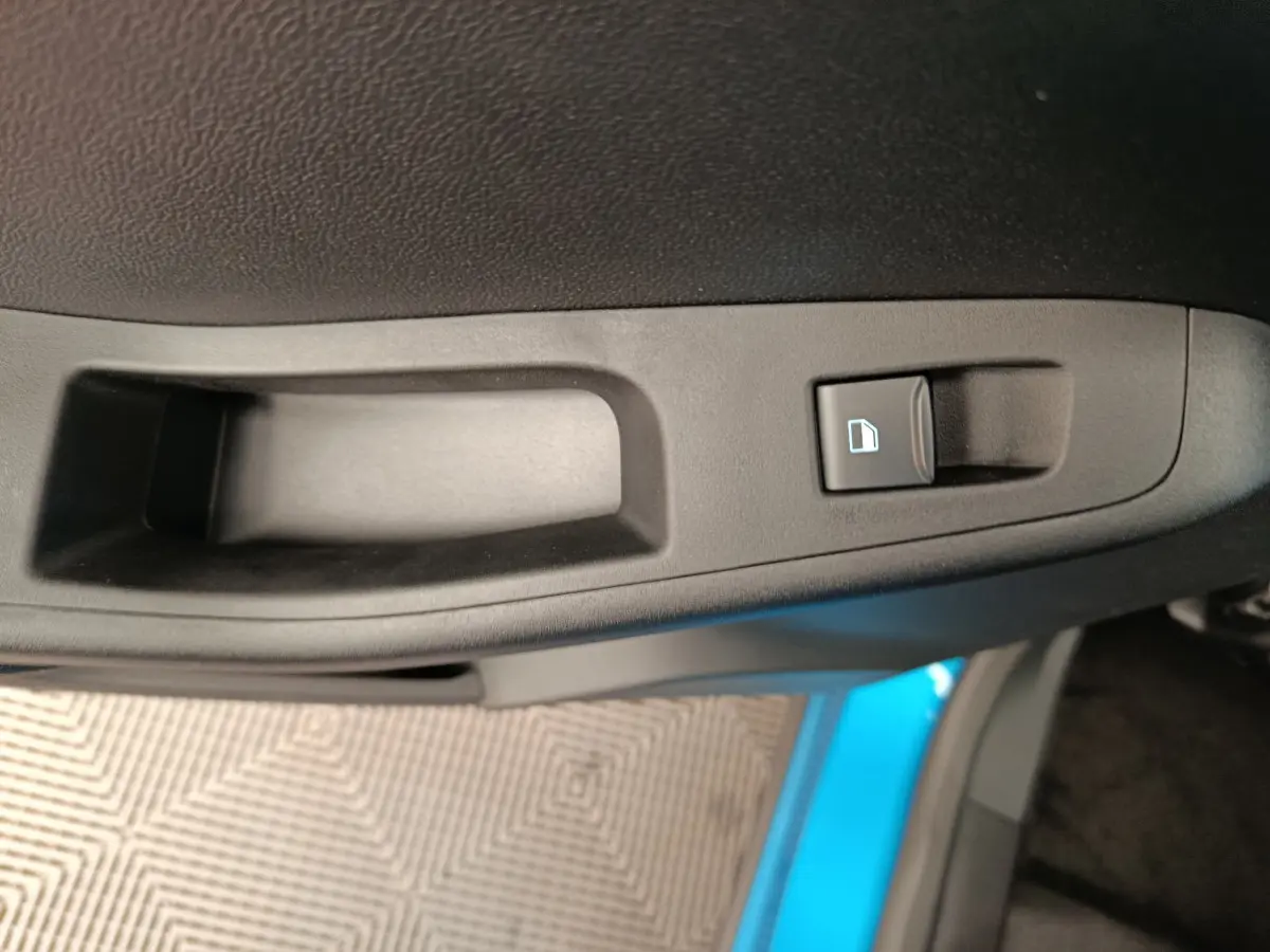 Gros plan sur la poignée intérieure de porte côté conducteur du Ford Puma bleu 2025 avec bouton de verrouillage.