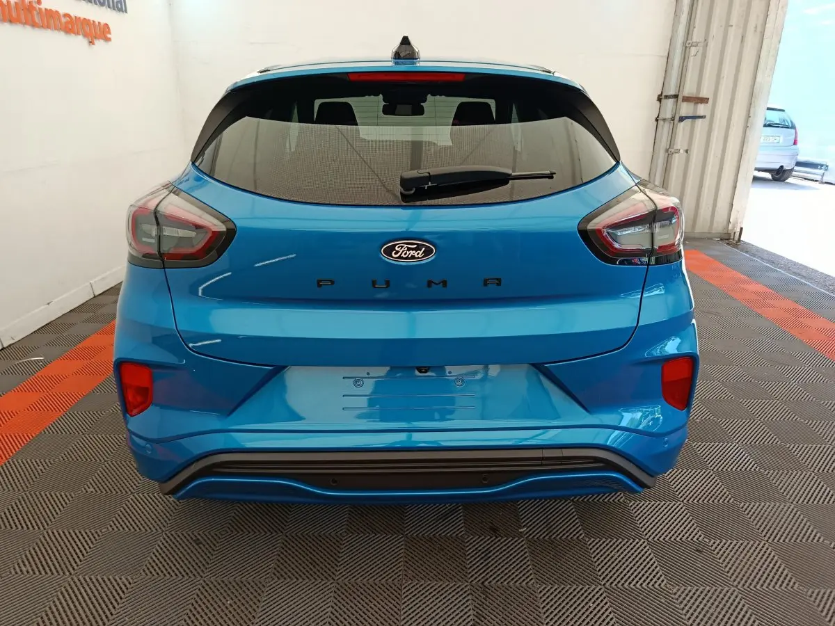 Vue arrière d'un Ford Puma bleu 2025 avec feux LED et logo Ford bien visibles sur un sol à damiers.