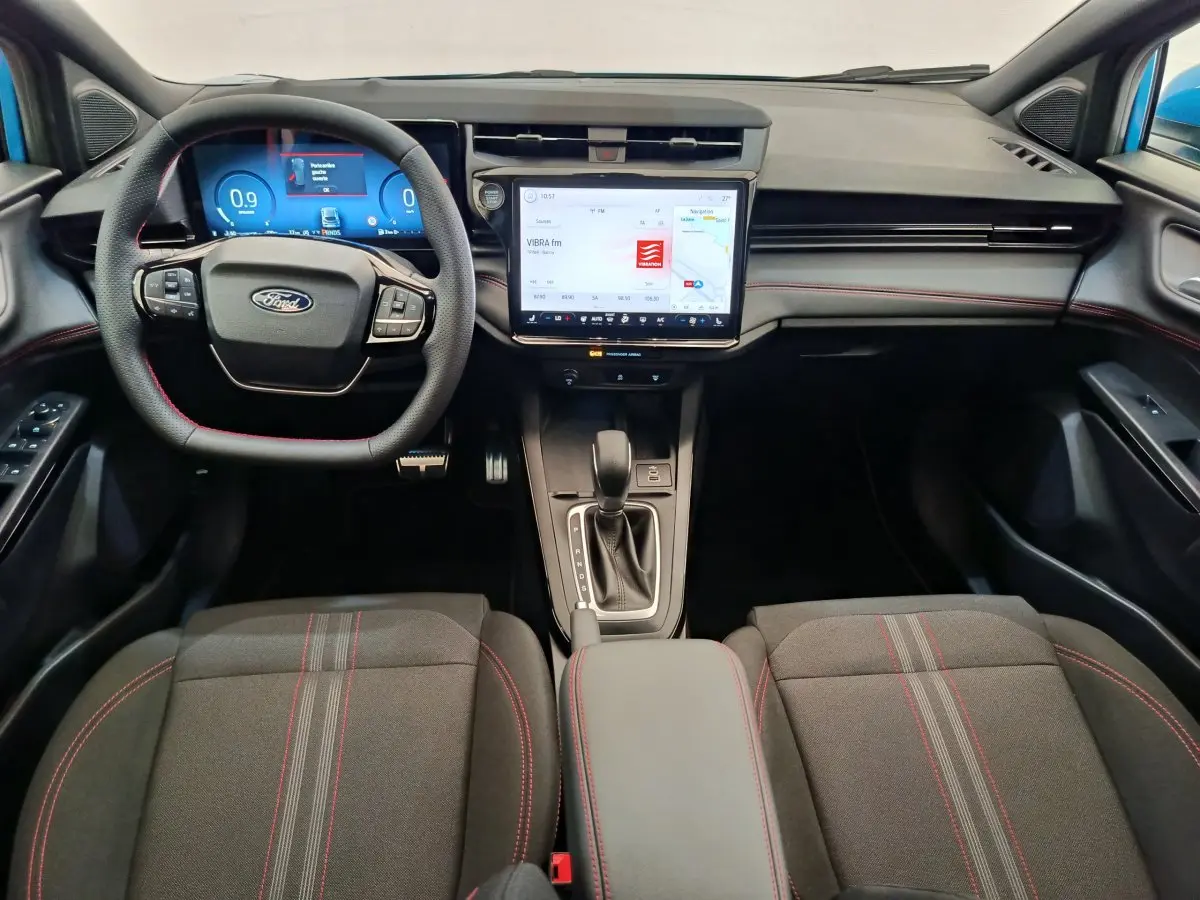 Vue intérieure avant du Ford Puma bleu 2025, tableau de bord moderne avec écran tactile central et volant multifonctions.