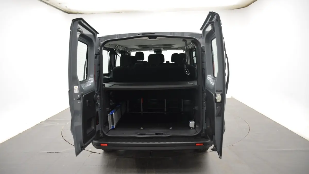 Vue arrière du Renault Trafic Fourgon gris clair 2025, portes ouvertes montrant l’espace de chargement et la banquette arrière.