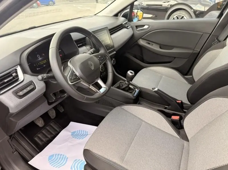 Vue intérieure côté conducteur de la Renault Clio V 1.5 DCI 100 Evolution 2025 avec volant, tableau de bord numérique et sièges gris.