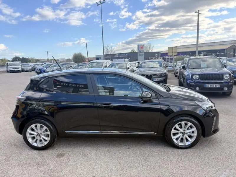 Profil côté gauche d'une Renault Clio V noire 2025, version 1.5 DCI 100 Evolution, garée en extérieur sur parking.