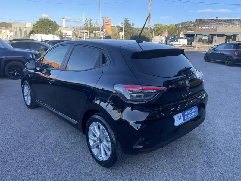 Renault Clio V noire vue en 3/4 arrière droit, avec feux arrière LED et jantes alliage visibles, stationnée en extérieur.