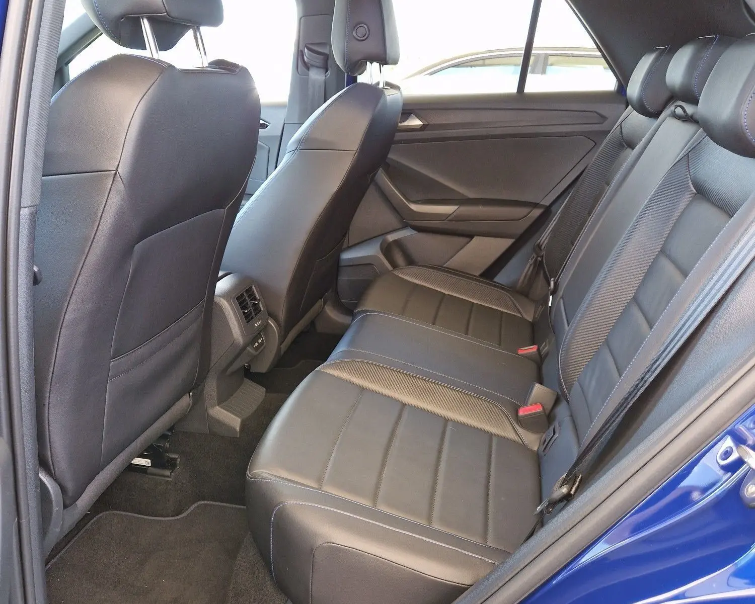 Vue intérieure arrière côté gauche du Volkswagen T-Roc bleu Lapiz avec sièges en cuir noir et finitions soignées.