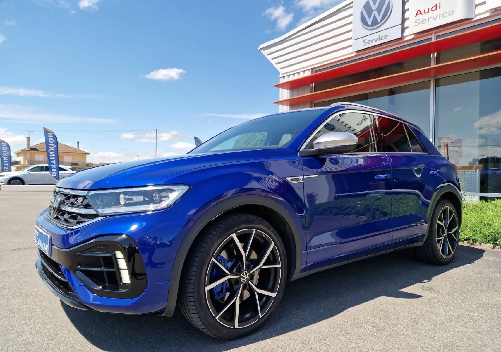 Volkswagen T-Roc 2.0 TSI bleu Lapiz en 3/4 avant droit, avec jantes noires et étriers de frein bleus visibles.