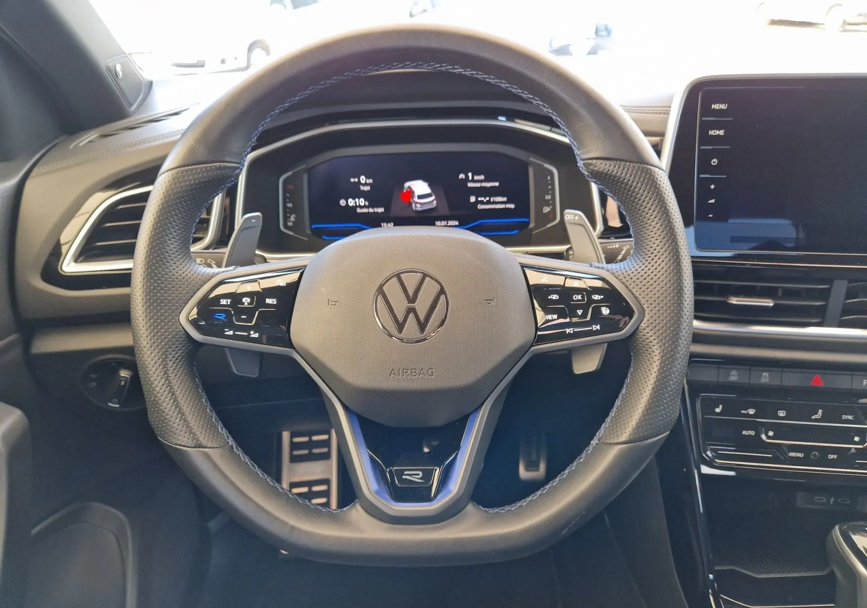 Volant en cuir noir avec surpiqûres bleues et tableau de bord numérique du Volkswagen T-Roc 2022.