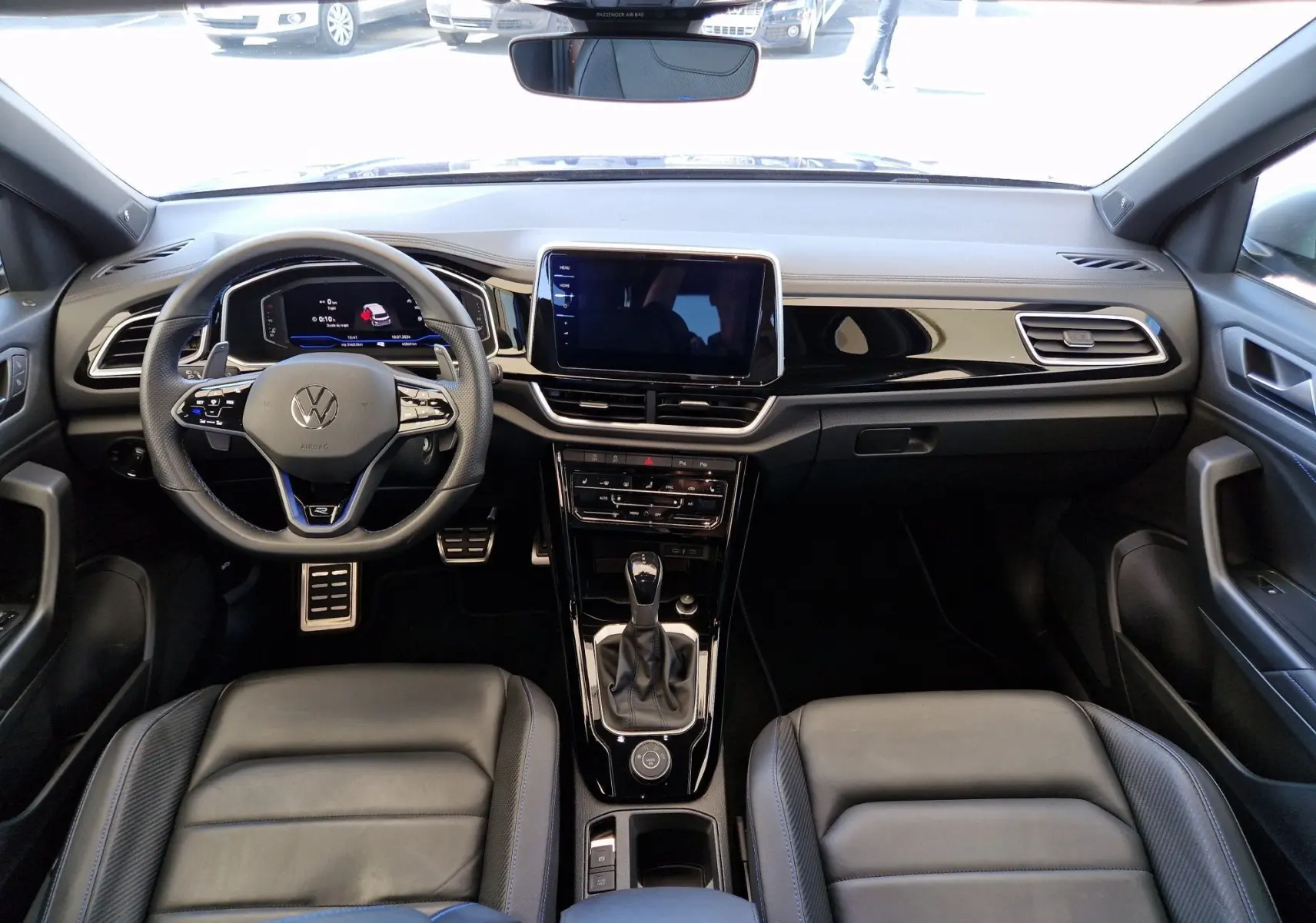 Intérieur du Volkswagen T-Roc 2022 en cuir noir, vue frontale du poste de conduite avec écran tactile central.