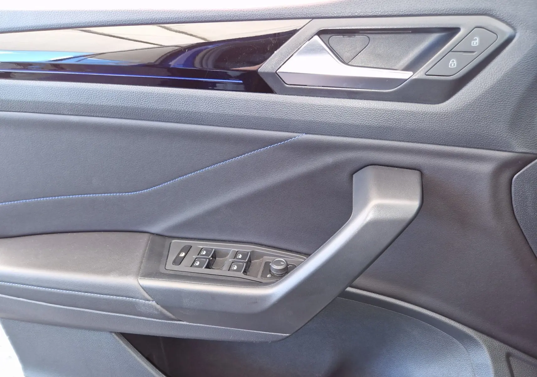 Détail de la porte côté gauche du Volkswagen T-Roc bleu Lapiz 2022 avec commandes de vitres et serrure intégrées.