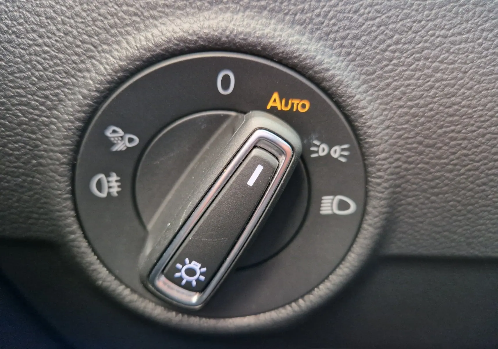 Gros plan sur le sélecteur d'éclairage noir du Volkswagen T-Roc 2022, avec mode auto et symboles lumineux blancs.