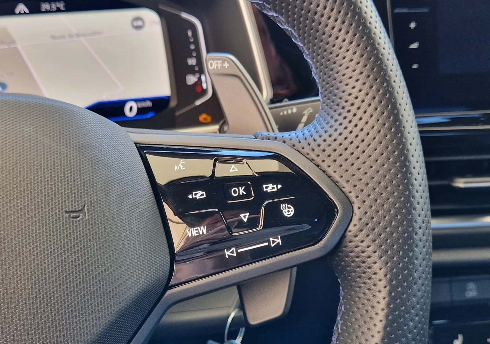 Gros plan sur le volant en cuir perforé du Volkswagen T-Roc 2022, avec commandes multifonctions côté gauche.
