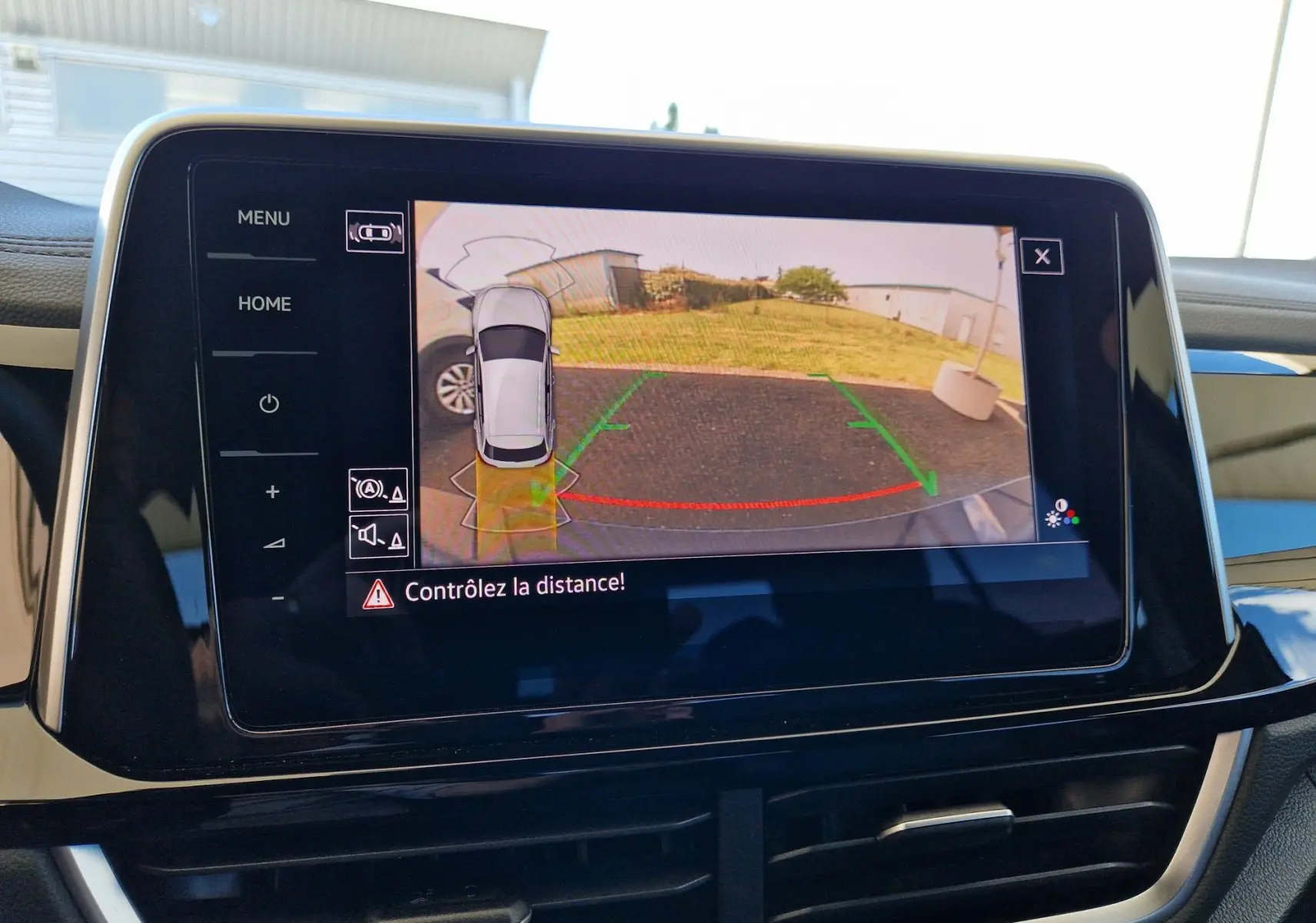 Écran tactile intérieur affichant la caméra de recul avec vue arrière et alertes de distance du Volkswagen T-Roc bleu Lapiz 2022.