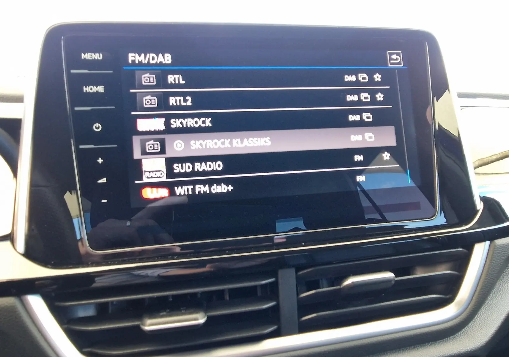 Écran tactile central du Volkswagen T-Roc 2022 affichant les stations radio FM/DAB avec commandes tactiles et aérateurs en dessous.