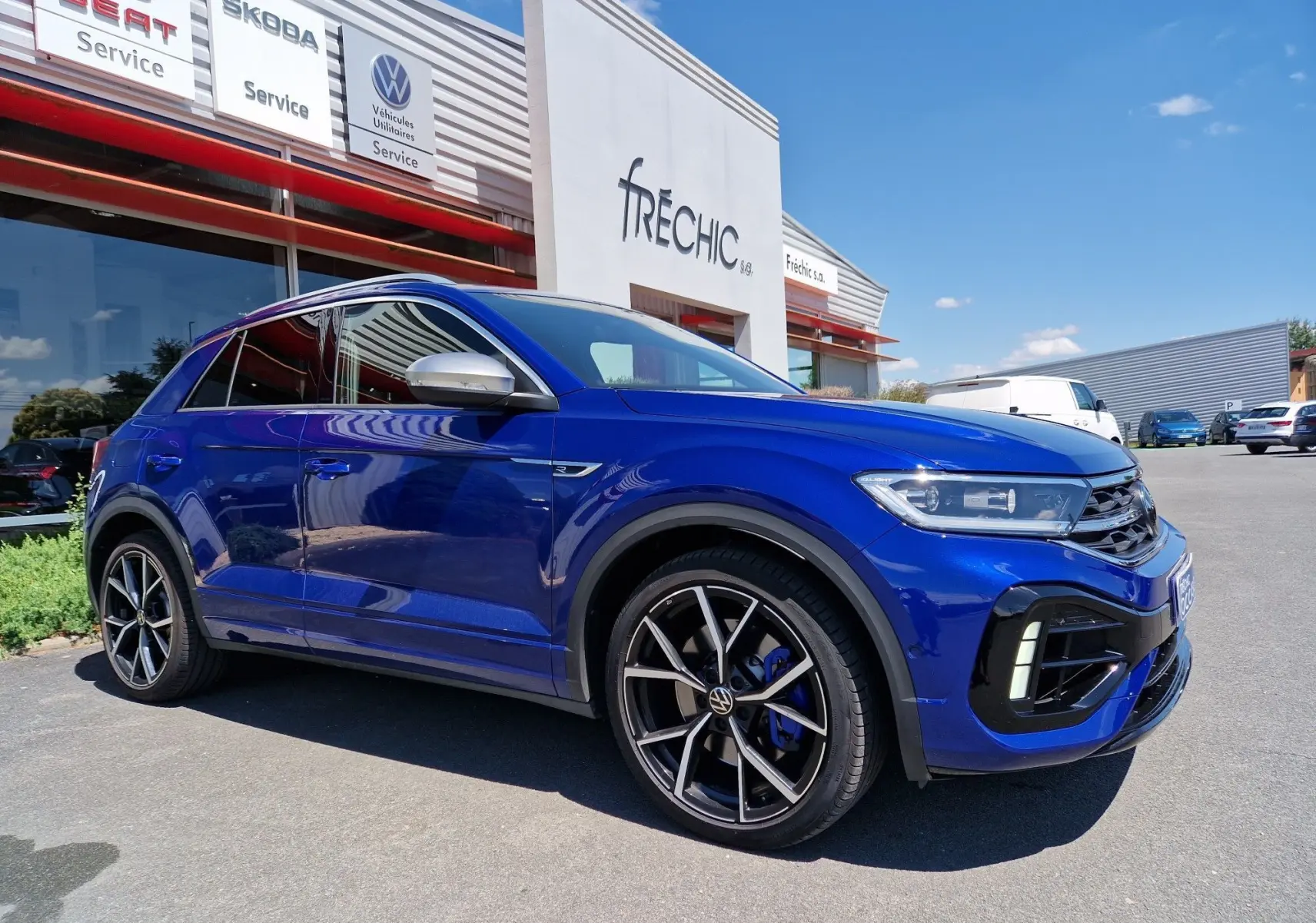 Volkswagen T-Roc bleu Lapiz en 3/4 avant droit, avec jantes noires et étriers de frein bleus visibles.