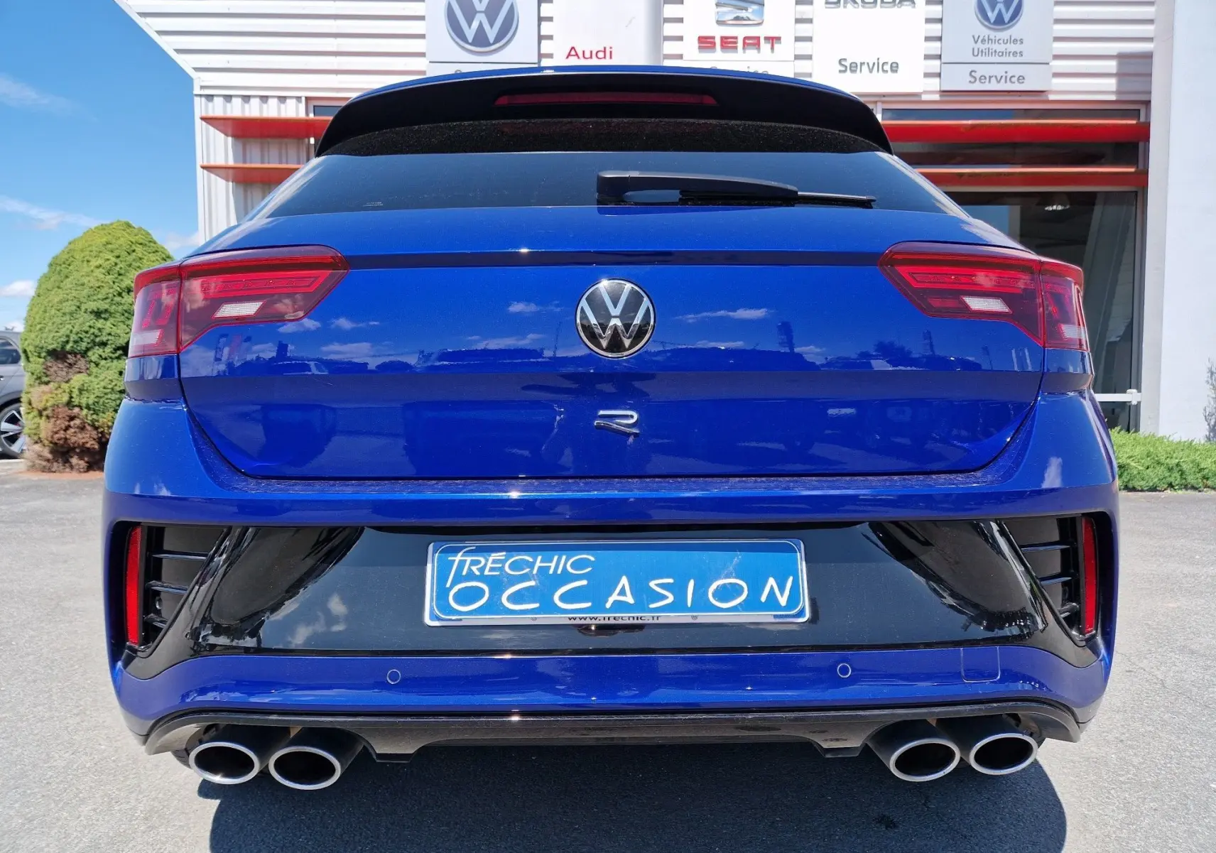 Vue arrière d'un Volkswagen T-Roc R bleu Lapiz avec double sortie d'échappement et logo distinctif R visible.