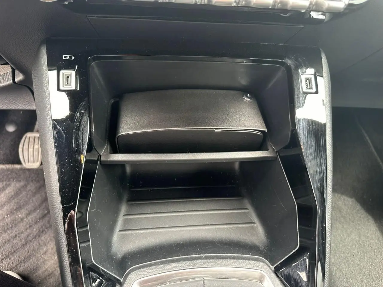 Gros plan sur la console centrale noire brillante du Peugeot 2008 II, avec prises USB visibles de chaque côté.