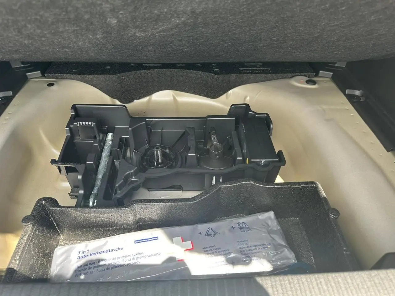 Coffre ouvert d'une Peugeot 2008 gris clair montrant le rangement sous plancher avec kit de dépannage pneumatique.