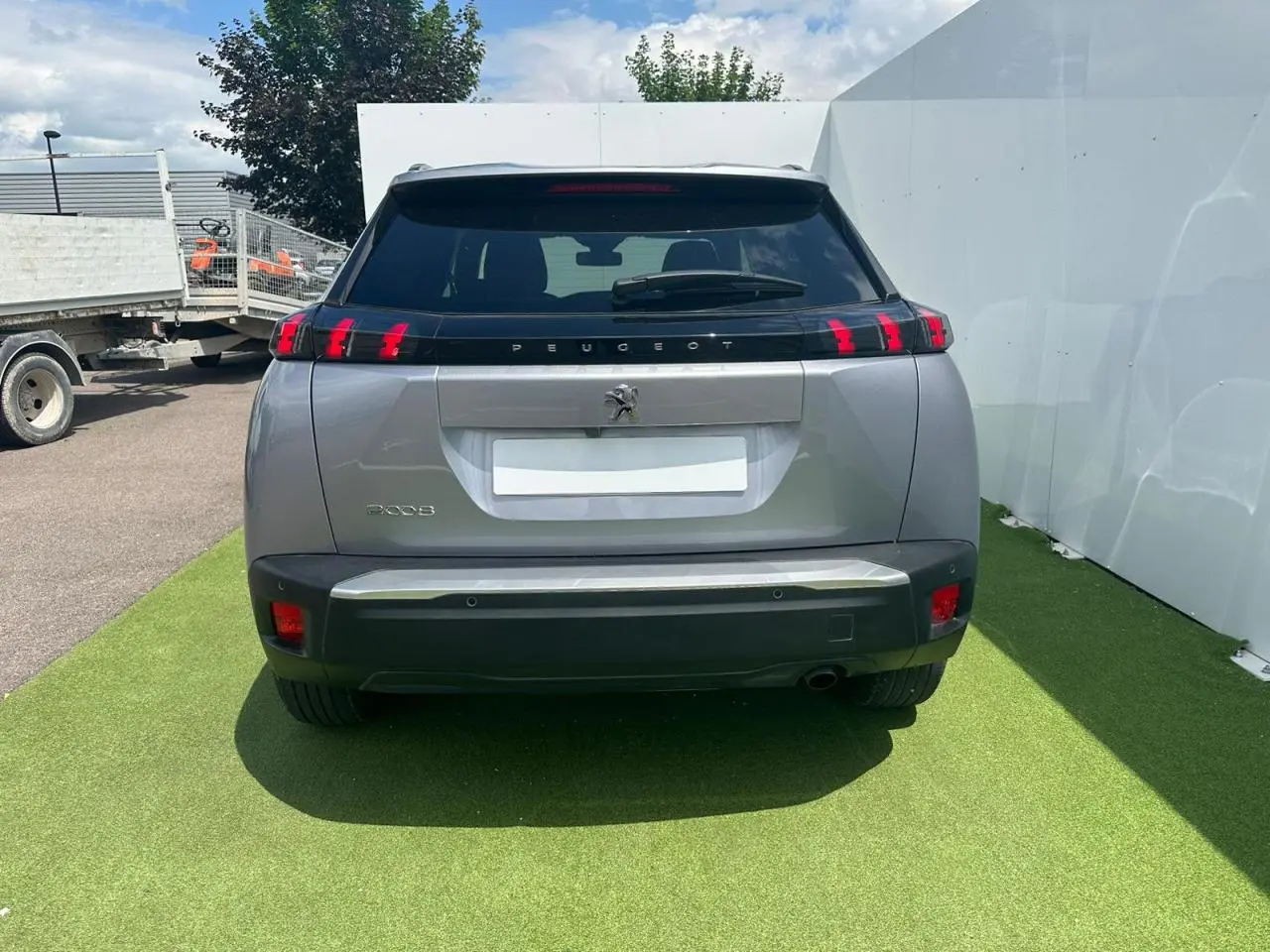 Vue arrière d'un Peugeot 2008 gris clair avec feux arrière à trois griffes rouges et becquet noir brillant.