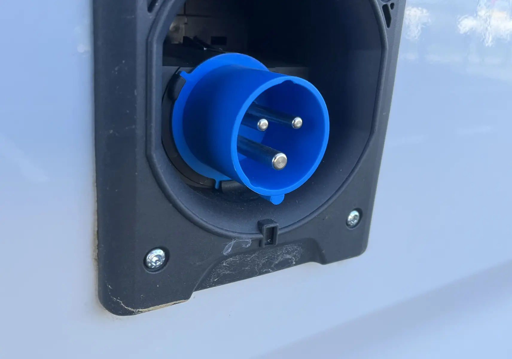 Gros plan sur la prise électrique bleue encastrée dans la carrosserie blanche glacée du Toyota Proace City 2023.