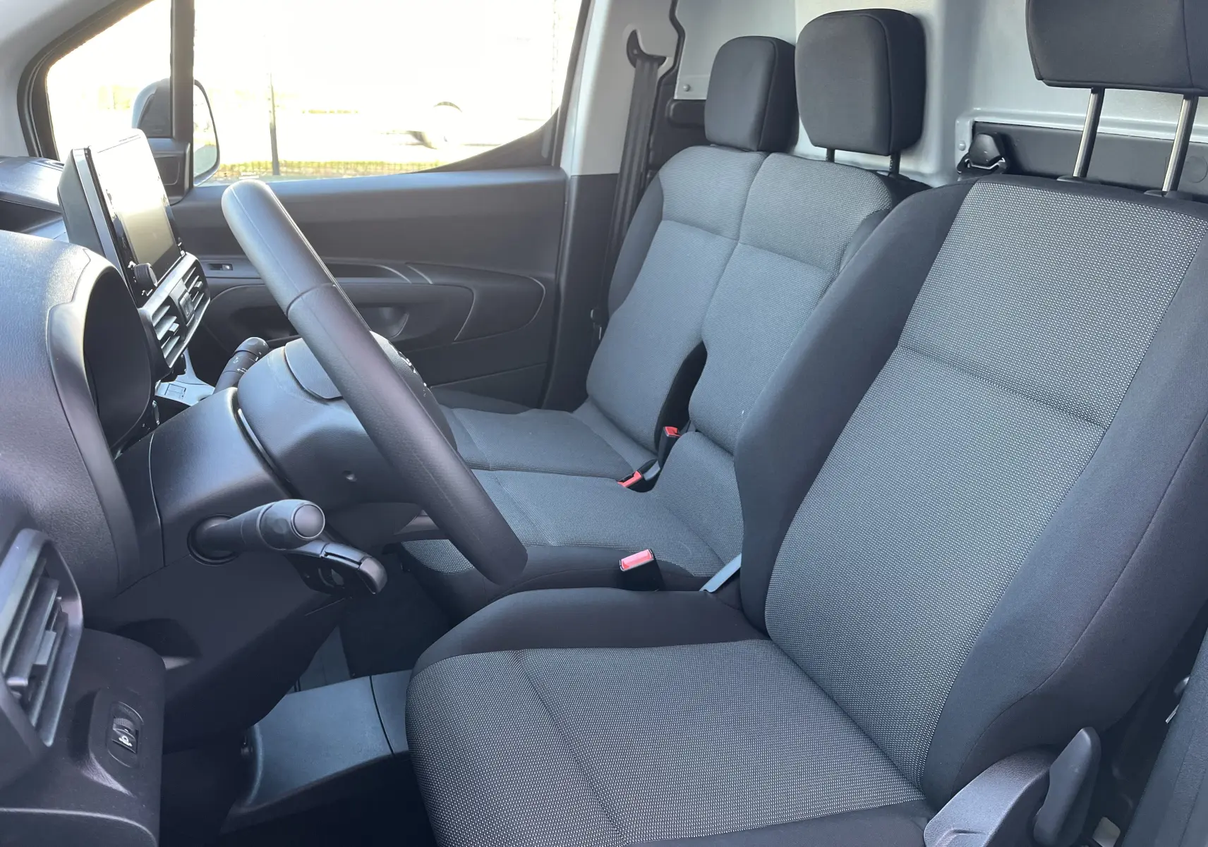 Vue intérieure côté conducteur du Toyota Proace City 2023, sièges tissu gris et tableau de bord moderne.