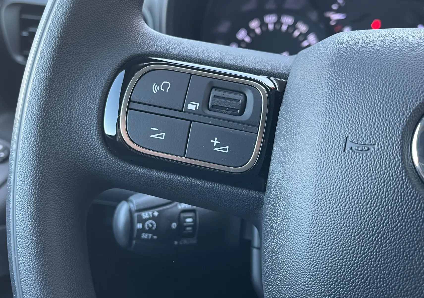 Gros plan sur les commandes du volant à gauche du Toyota Proace City blanc glacier, montrant les boutons de volume et appel.