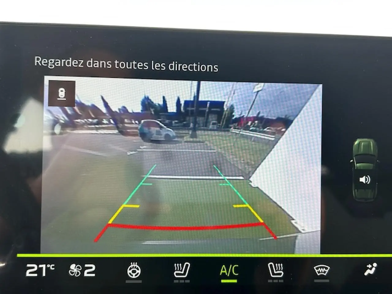 Vue caméra de recul du Dacia Duster III kaki dusty, affichant les lignes de guidage colorées et l'environnement arrière du véhicule.