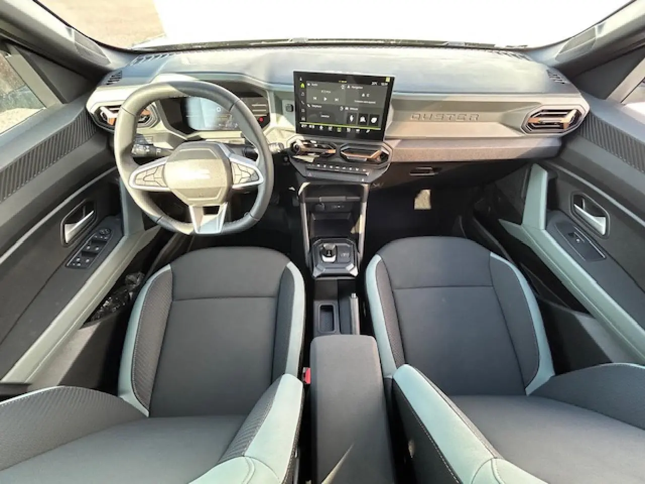 Vue intérieure avant du Dacia Duster III 1.6 Hybrid 140 avec tableau de bord digital et sellerie TEP MicroCloud kaki lichen.