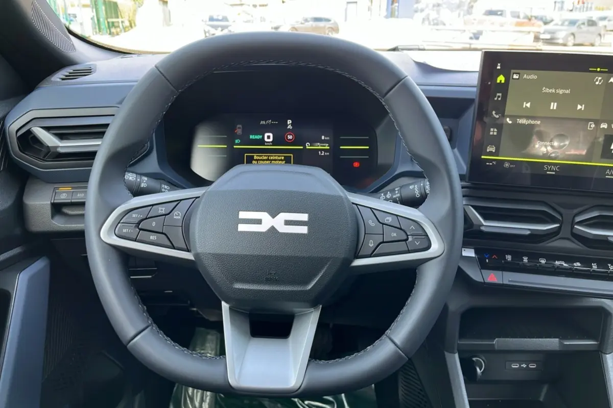 Vue centrée sur le volant cuir noir du Dacia Bigster Hybrid 155 Expression Plus avec tableau de bord numérique et écran tactile.