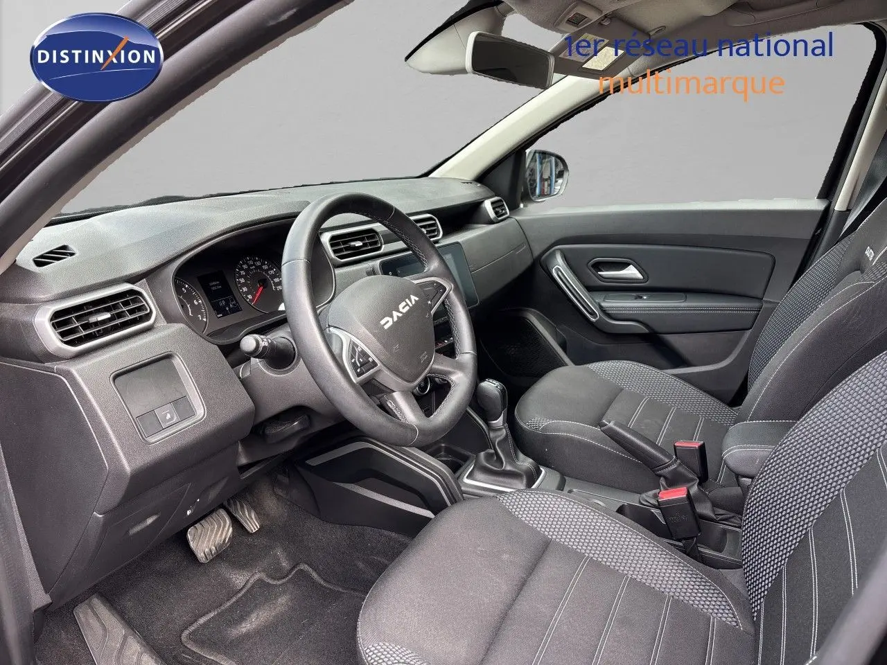 Vue intérieure avant du tableau de bord et volant noir du Dacia Duster Journey TCe 150 EDC 2024 avec écran tactile central.