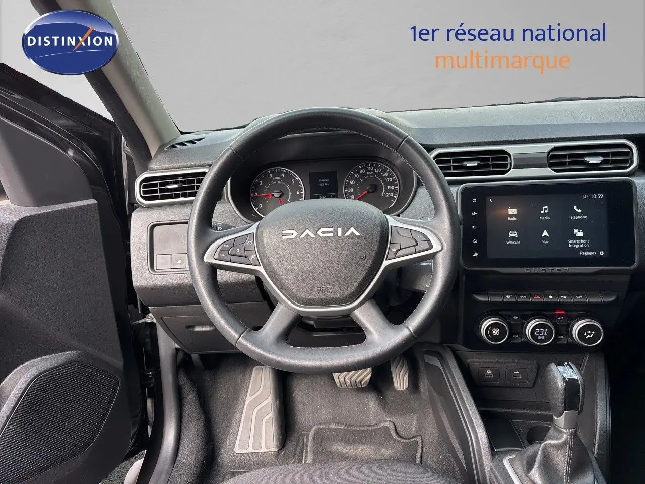 Vue intérieure centrée sur le volant et tableau de bord du Dacia Duster noir 2024 avec écran tactile et boîte automatique.
