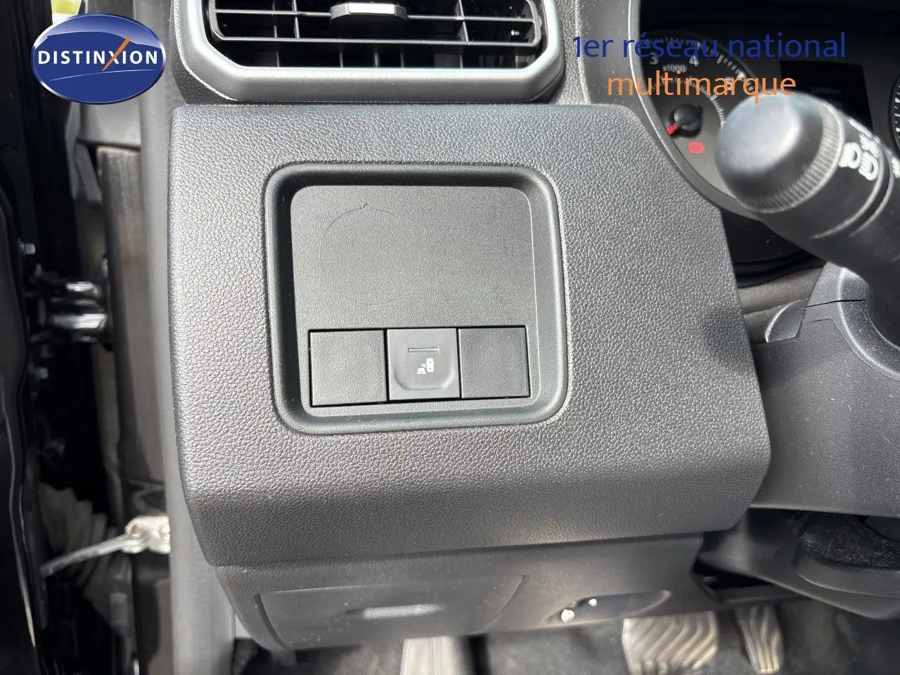 Gros plan sur le tableau de bord côté gauche d’un Dacia Duster noir 2024, montrant un bouton de commande.