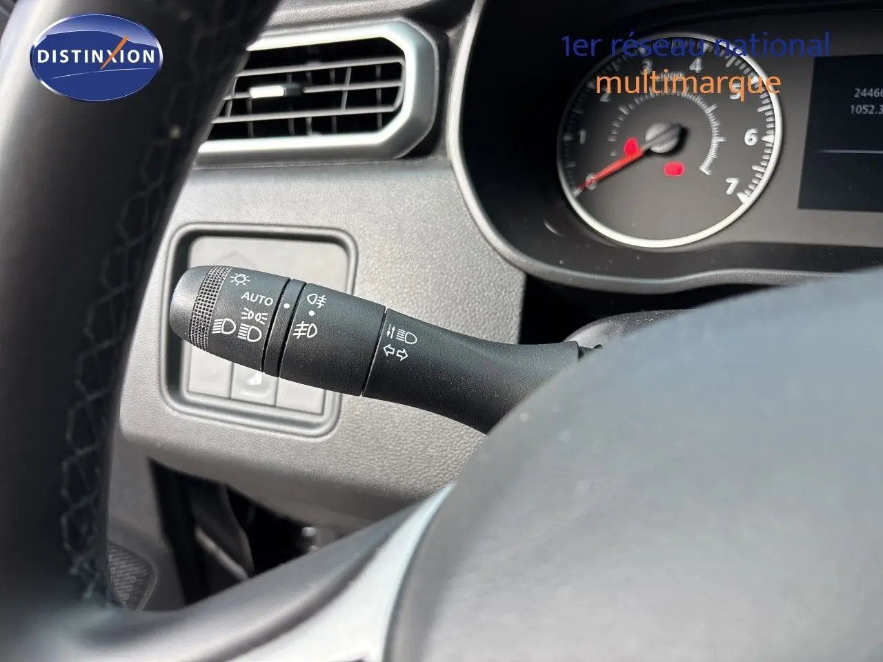 Gros plan sur la commande des phares à gauche du volant dans l'habitacle du Dacia Duster noir 2024.