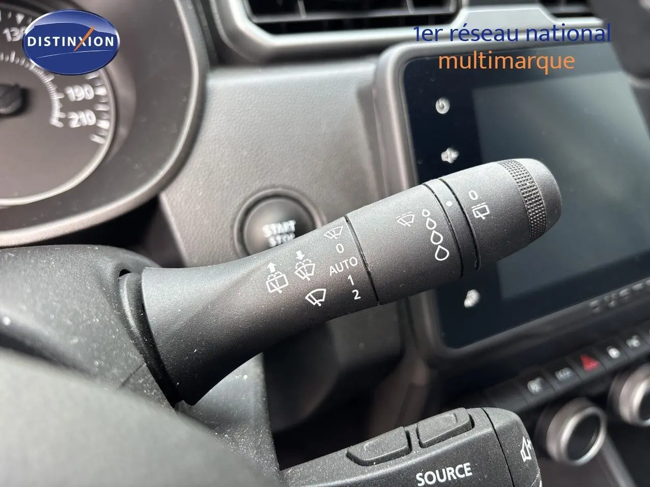Gros plan sur la commande des essuie-glaces à l'intérieur du Dacia Duster noir, avec tableau de bord et écran tactile en arrière-plan.