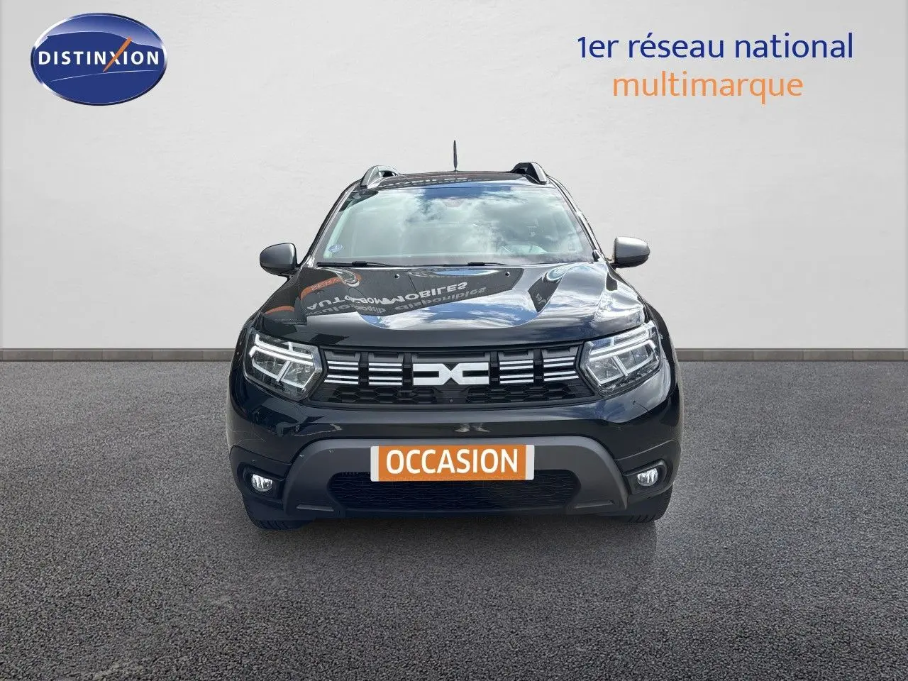 Vue avant du Dacia Duster noir 2024 avec calandre distinctive et phares LED allumés sur fond neutre.