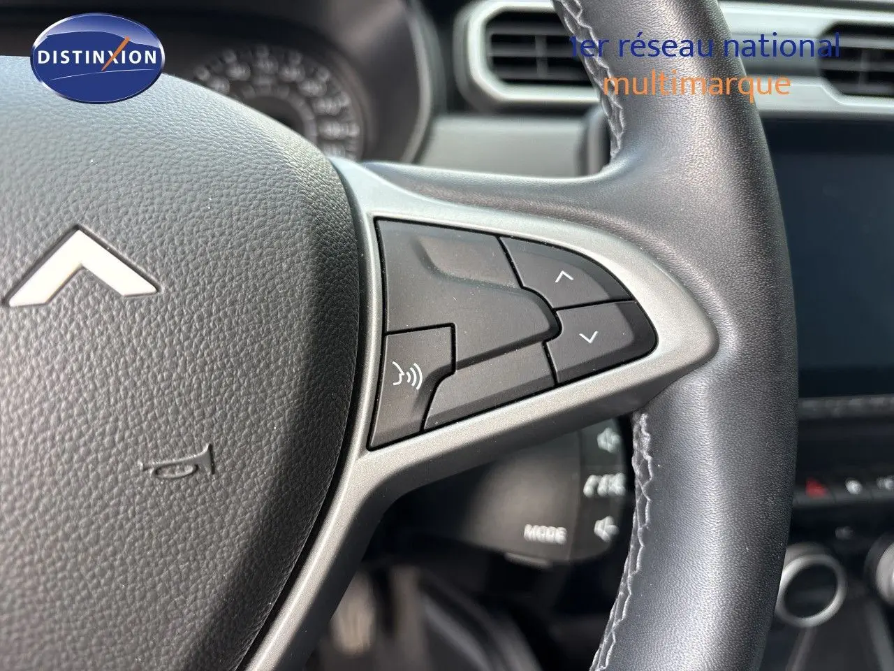Gros plan sur le volant noir du Dacia Duster 2024, mettant en valeur les commandes multifonctions côté droit.