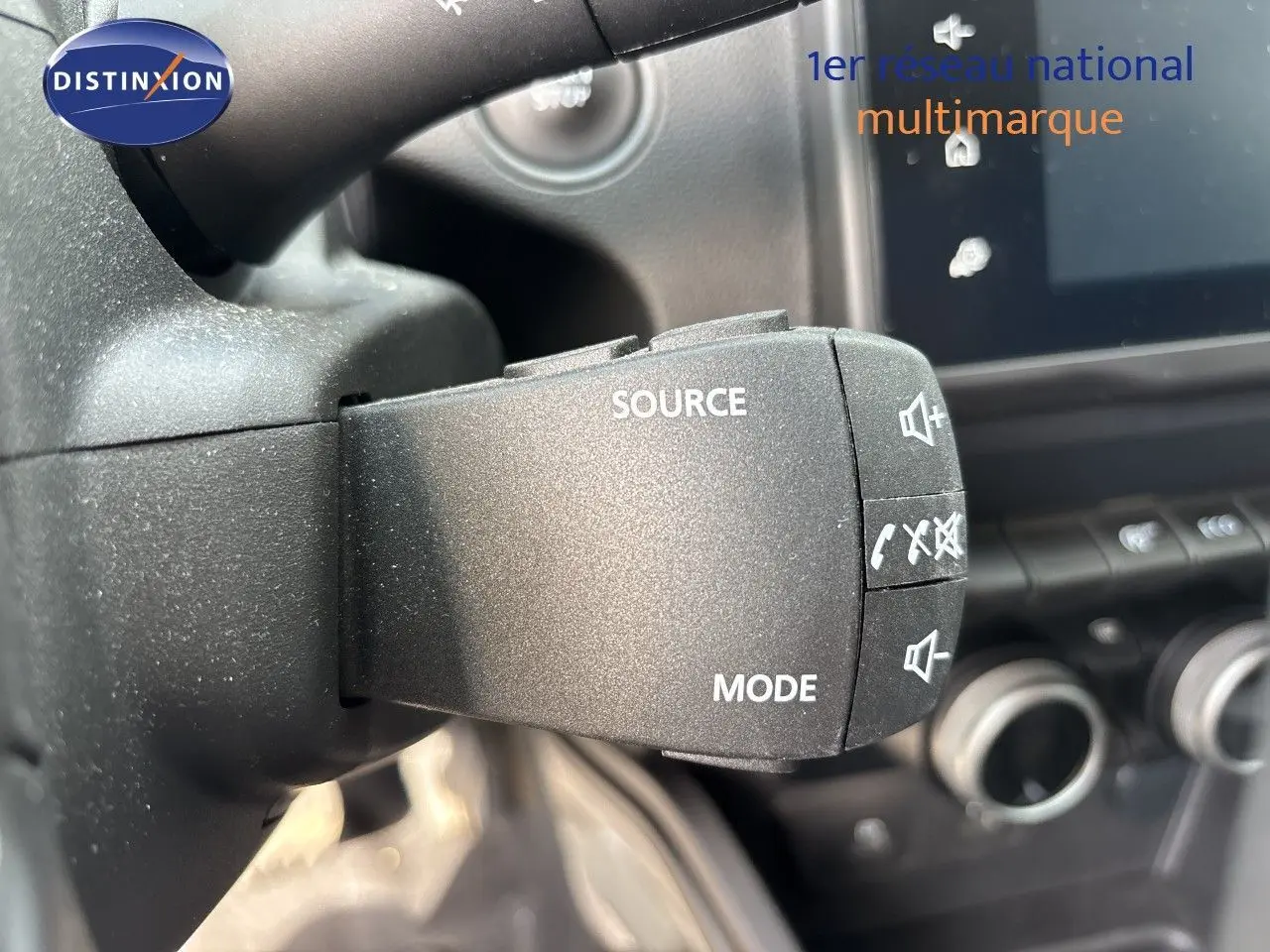 Gros plan sur la commande au volant du Dacia Duster 2024, mettant en valeur les boutons source et mode.