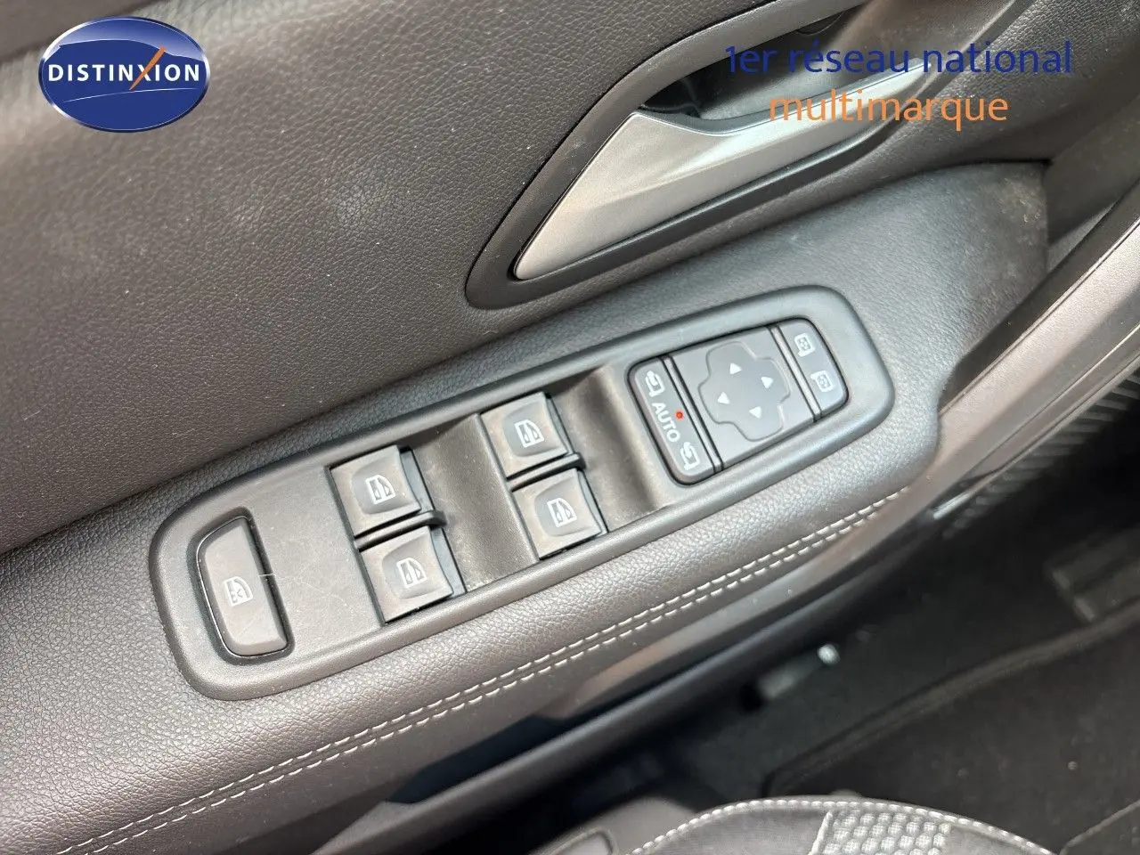 Gros plan sur les commandes des vitres électriques côté conducteur du Dacia Duster Journey noir, avec surpiqûres blanches visibles.