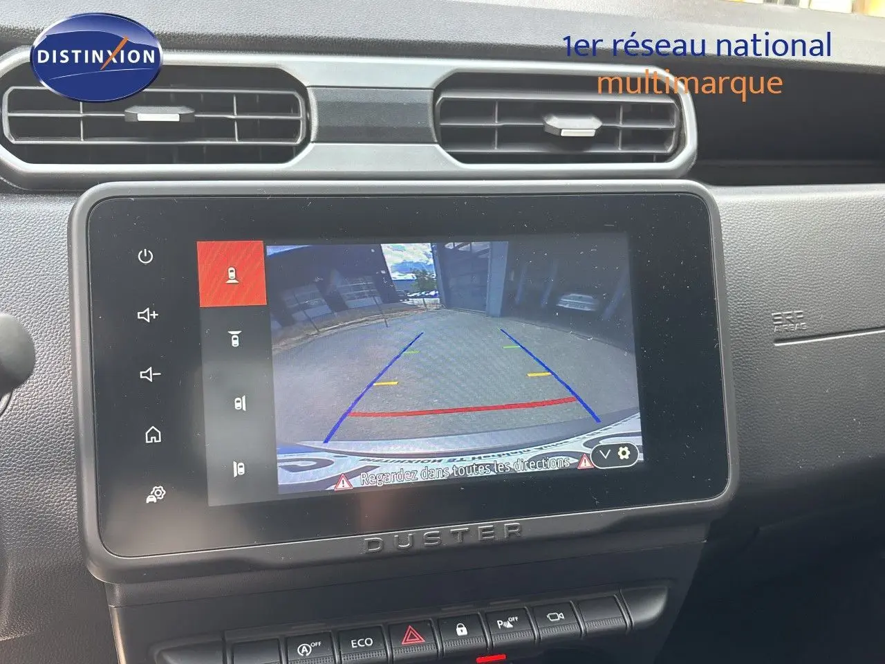 Écran central du Dacia Duster 2024 noir montrant la caméra de recul avec lignes de guidage colorées.