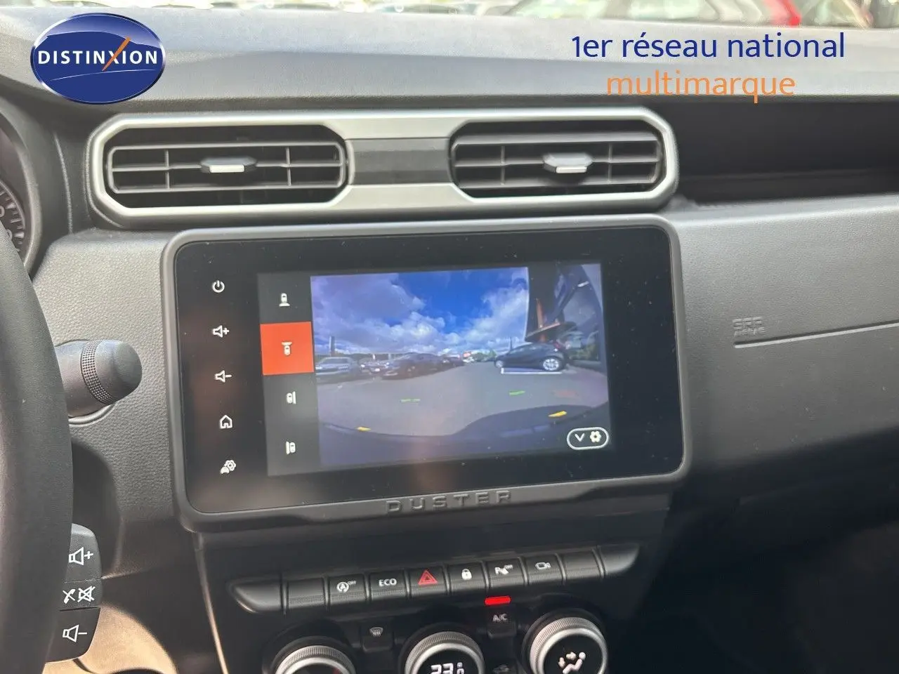 Intérieur du Dacia Duster 2024 noir, vue sur l’écran central tactile affichant la caméra de recul et la console de climatisation.