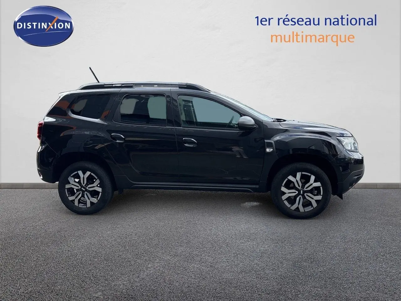 Profil côté gauche du Dacia Duster Journey TCe 150 EDC noir 2024 avec jantes bi-ton et toit équipé de barres de toit.