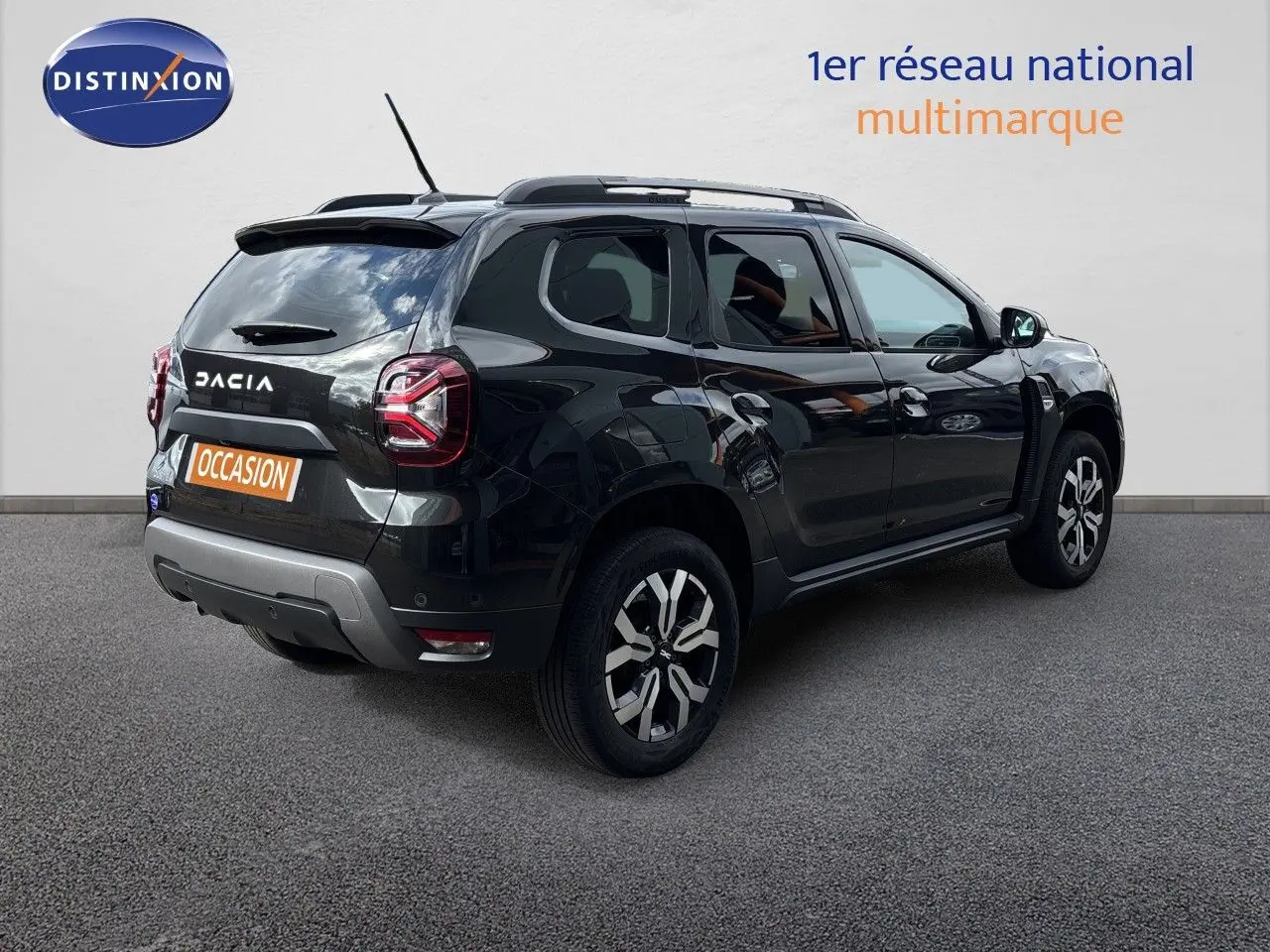 Dacia Duster noir en 3/4 arrière droit, avec jantes bi-ton et toit équipé de barres de toit.