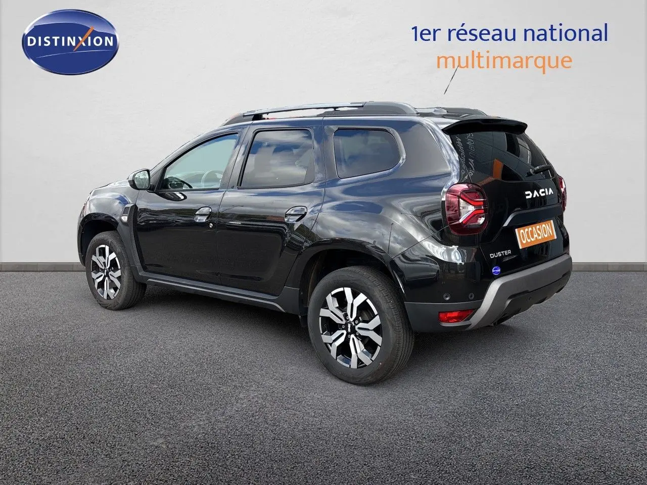 Vue 3/4 arrière droite d'un Dacia Duster noir 2024 avec jantes bi-ton et logo visible sur le hayon.
