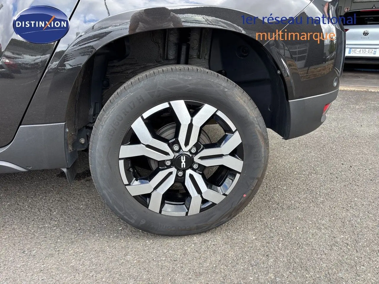 Gros plan sur la roue arrière droite du Dacia Duster noir 2024 avec jante alliage bicolore distinctive.